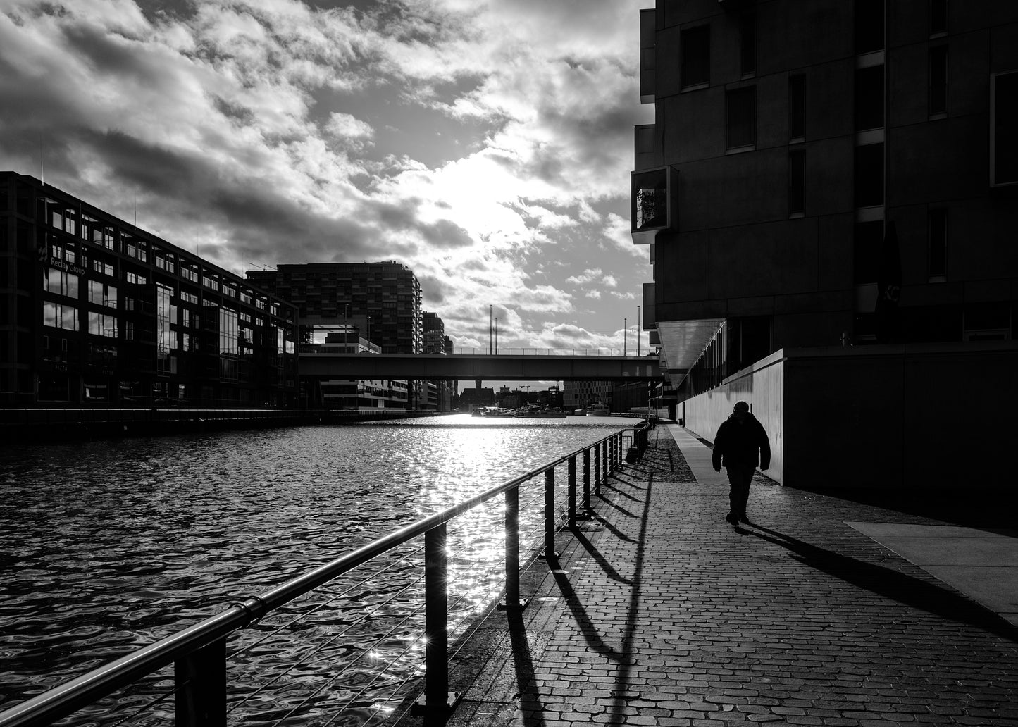 Mann spaziert am Kölner Hafen mit Severinsbrücke Sonne und Wolken